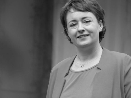 Frau in Businessoutfit vor unscharfem Hintergrund.